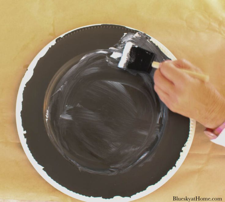 a person is painting a black plate with white paint