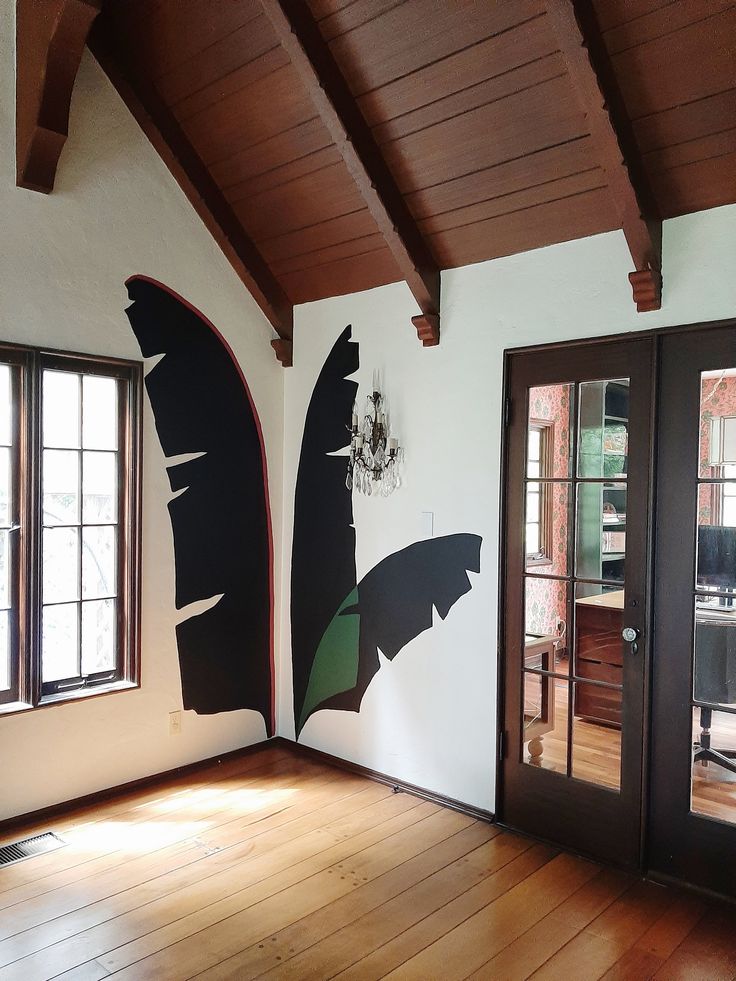 an empty room with wood flooring and painted black bats on the wall behind glass doors