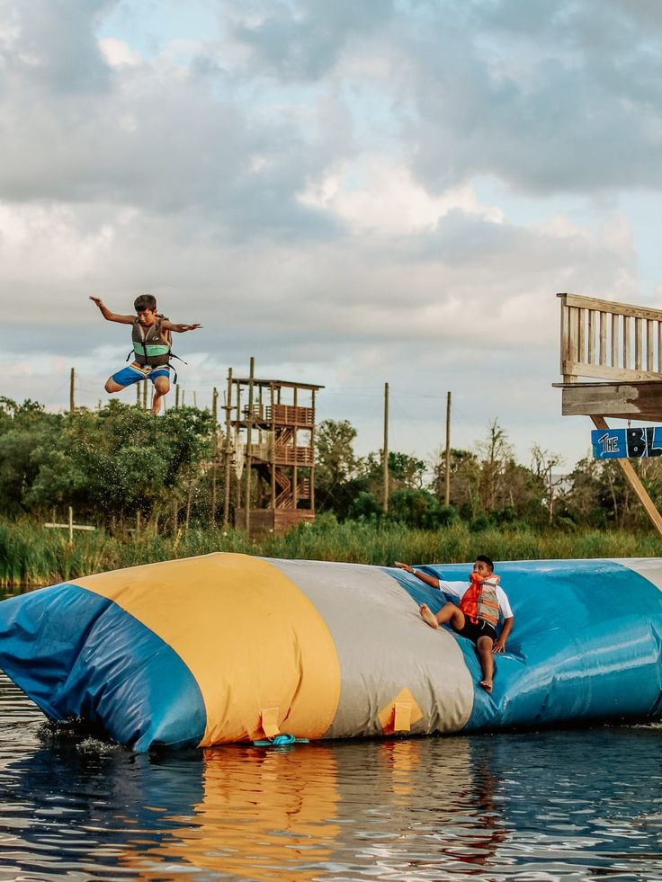 a man is jumping off the top of a water slide while another person jumps in the air