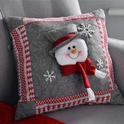 a snowman pillow sitting on top of a gray couch