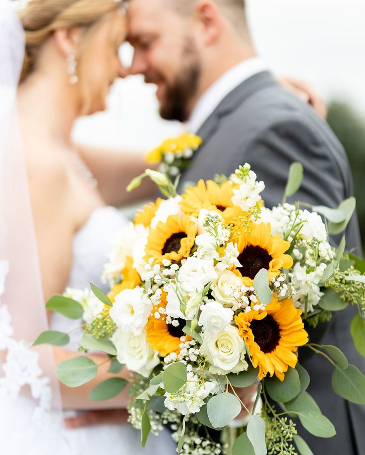 the bride and groom are posing for a photo together with sunflowers in their bouquet