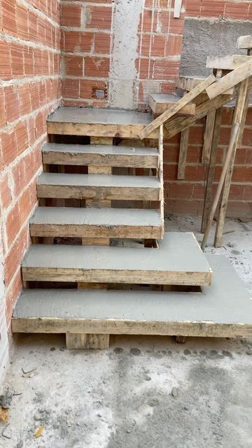 some stairs made out of wooden pallets next to a brick wall and cement floor