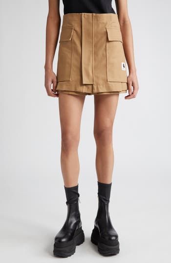 The iconic Japanese label and the American workwear brand get 'er done, fashionwise, on this skort crafted from durable cotton canvas in a clever design. 14 1/2" length; 2 1/2" inseam; 26" leg opening (size Small) Zip fly with button closure; front zip placket Front dual-entry pockets; back patch pockets 100% cotton Dry clean Made in Japan Designer Clothing Fall Cotton Cargo Skirt With Pockets, Utility Cotton Cargo Skirt For Fall, Fall Utility Cotton Cargo Skirt, Cotton Cargo Skirt With Patch Pockets For Work, Utility Cotton Cargo Skirt With Belt Loops, Utility Cargo Skirt With Belt Loops In Cotton, Utility Cargo Skirt In Cotton With Belt Loops, Fitted Cotton Cargo Skirt With Multiple Pockets, Fitted Beige Cotton Cargo Skirt