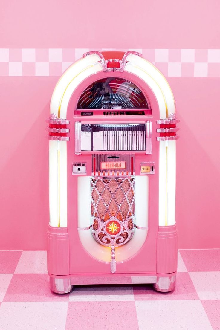 a pink jukebox machine sitting on top of a checkered floor in front of a pink wall