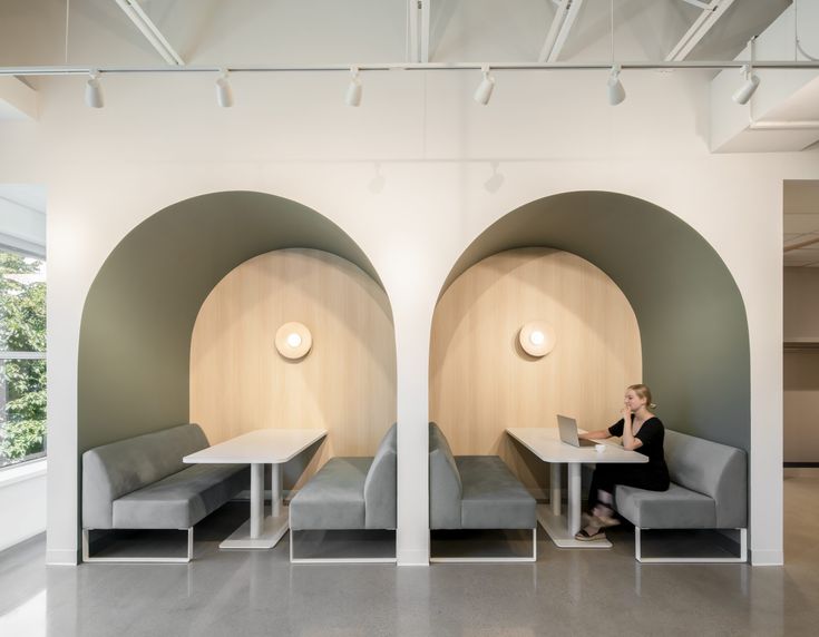 a woman sitting at a table with a laptop in front of two circular shaped booths