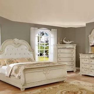 a white bed sitting in a bedroom on top of a hard wood floor next to a window