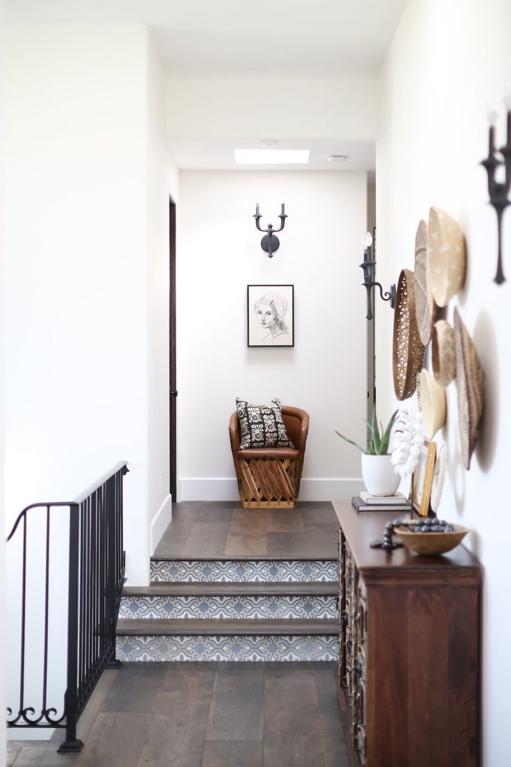 an entry way with stairs and decorative wall hangings on the walls, along with a wooden bench