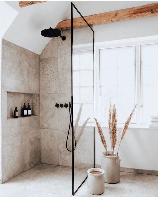 a bathroom with a tub, shower head and two planters in the corner on the floor