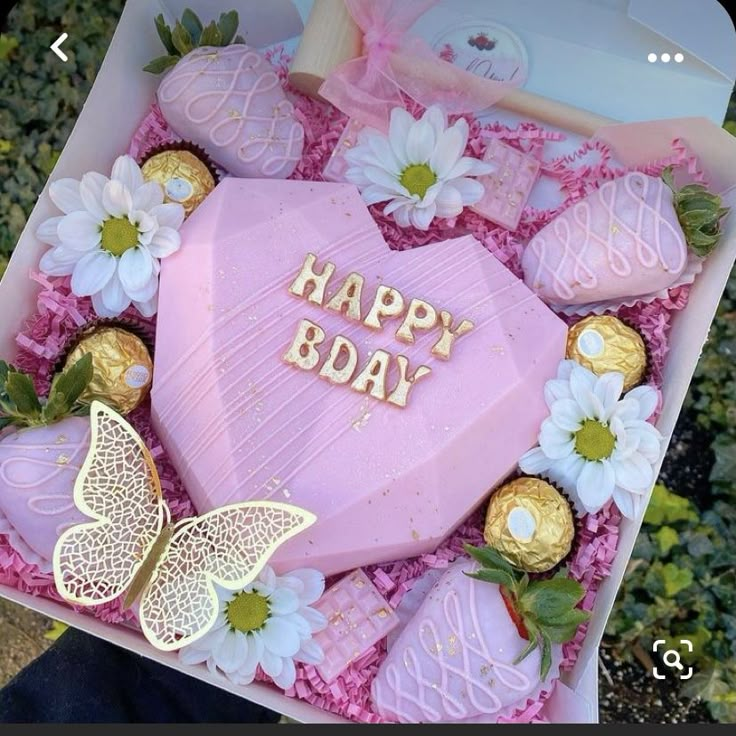 a pink heart shaped box filled with chocolates and flowers