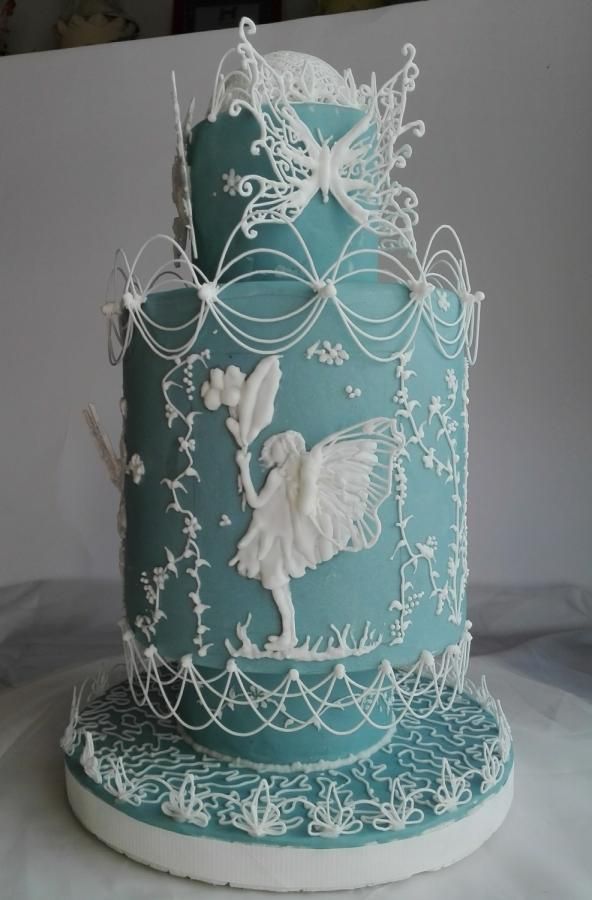 a blue and white cake with angel decorations on it