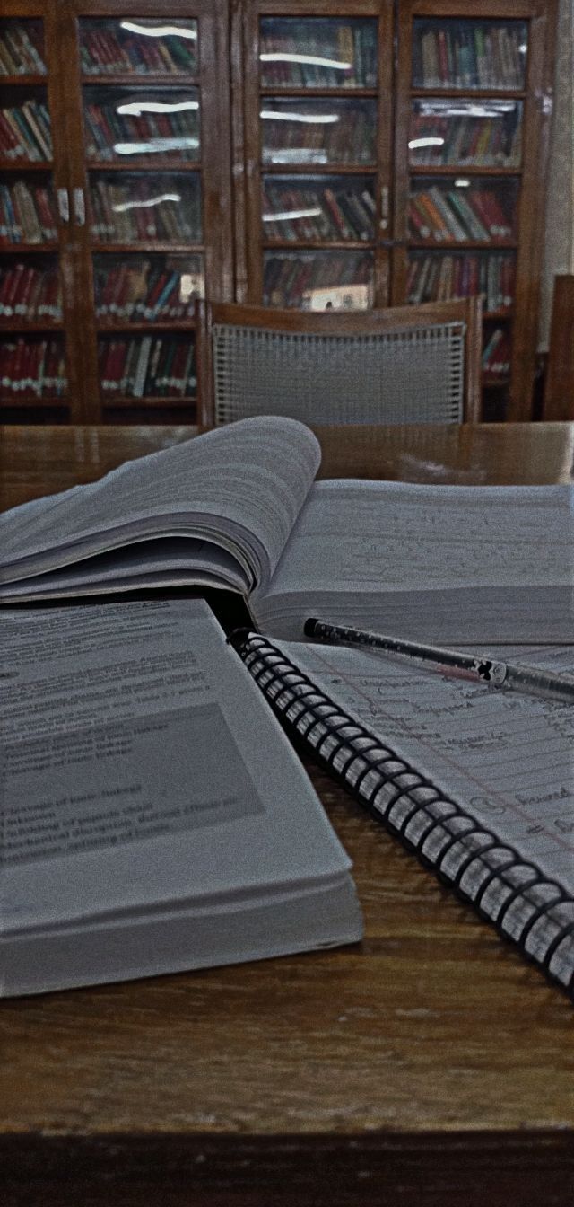 an open book sitting on top of a wooden table next to a pile of books