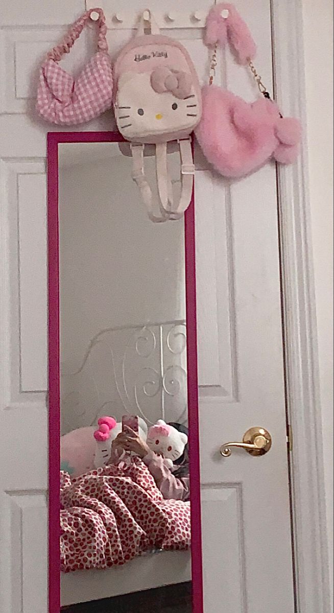 a hello kitty mirror hanging on the side of a white door with pink trimming