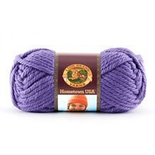 a ball of yarn that is purple and has a brown label on the end of it