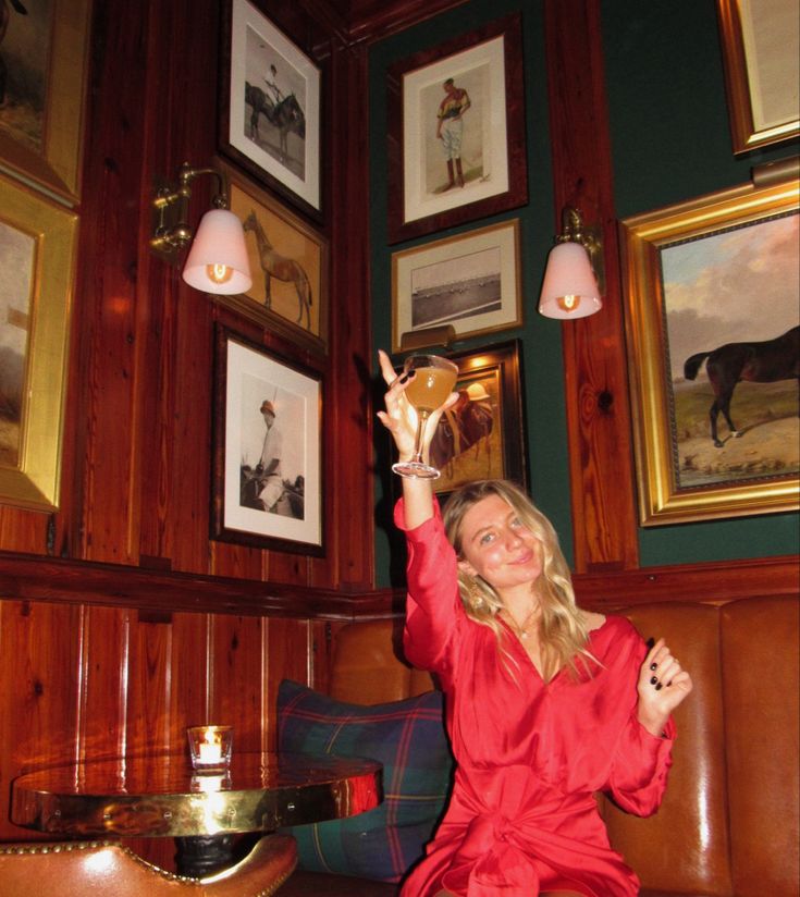 a woman in a red robe is sitting on a couch and holding up her hand