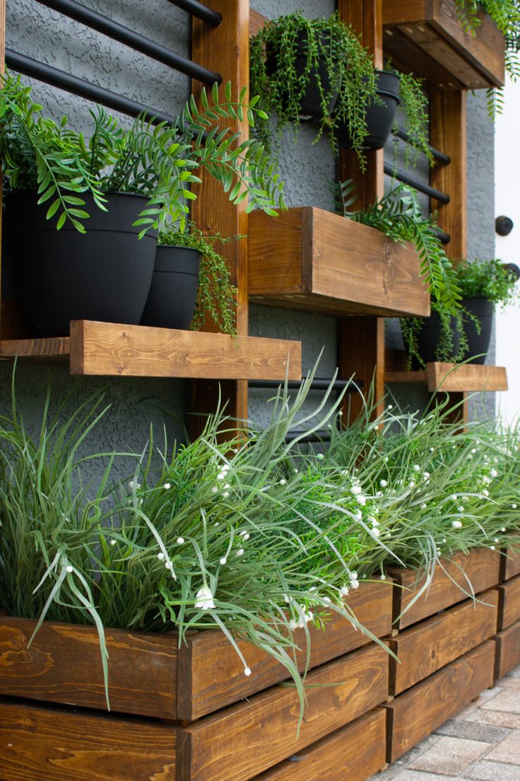 several wooden planters with plants in them on the side of a building that is decorated with greenery