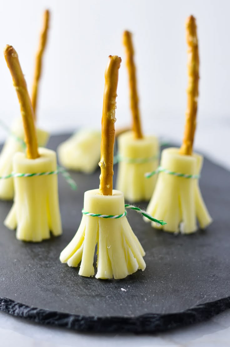 four small pieces of yellow cake sitting on top of a black plate with green string