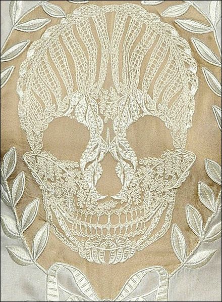 a white embroidered skull with leaves around it