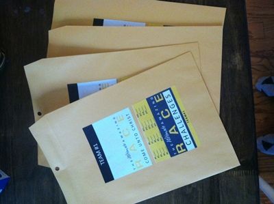 four brown envelopes sitting on top of a wooden table next to a pair of blue shoes