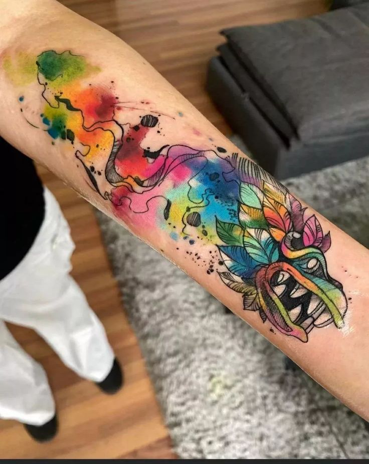 a colorful tattoo on the arm of a woman's arm with watercolor paint splat