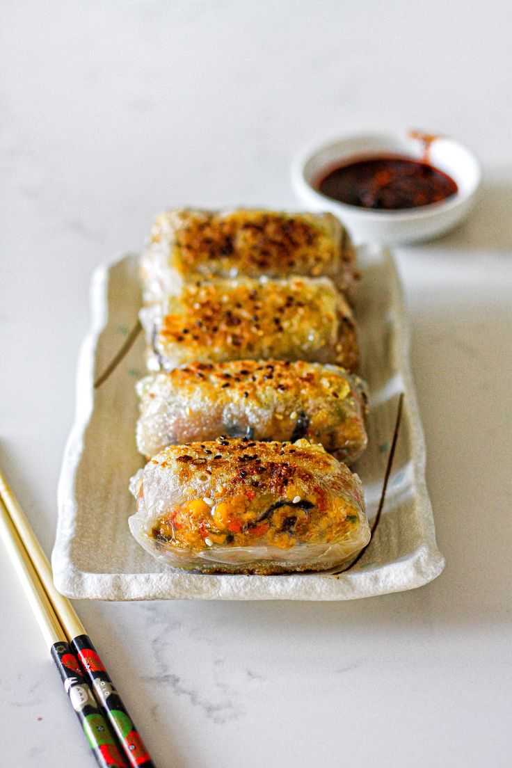 some food is sitting on a tray with chopsticks next to it and sauce