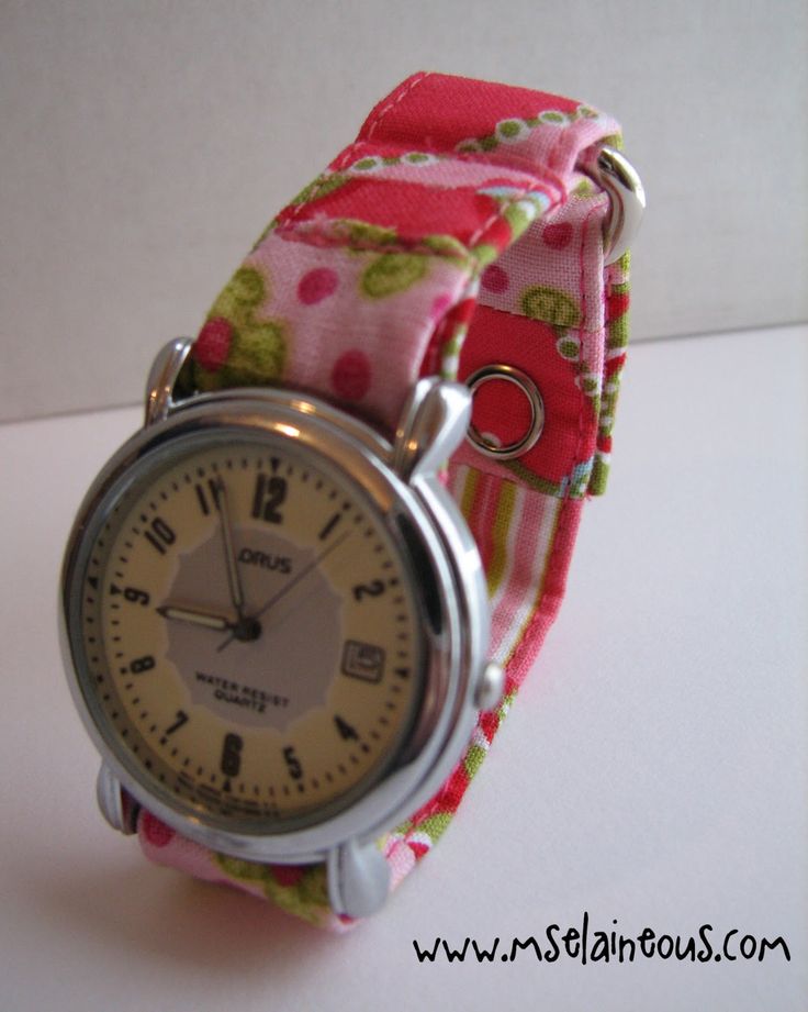 a watch with pink and green flowers on it sitting on a white counter top next to a wall