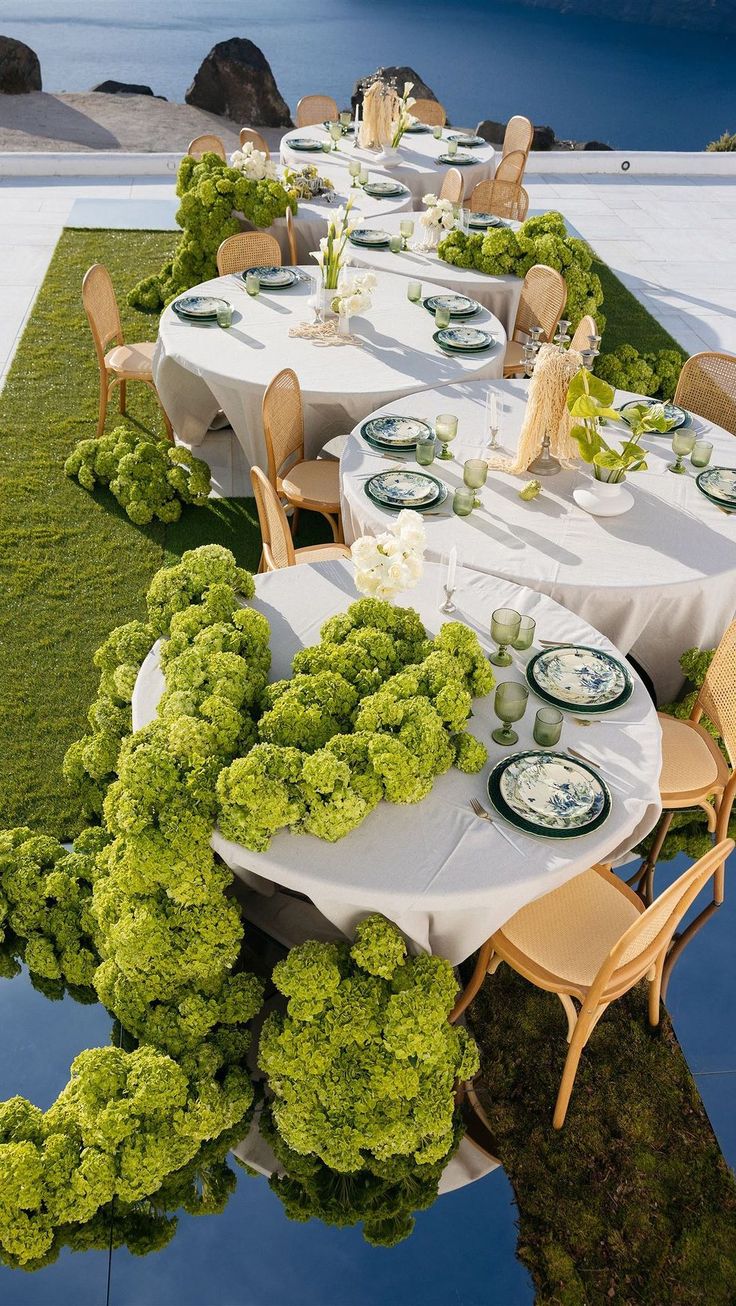 an outdoor dining area with tables and chairs covered in white tablecloths, surrounded by grass