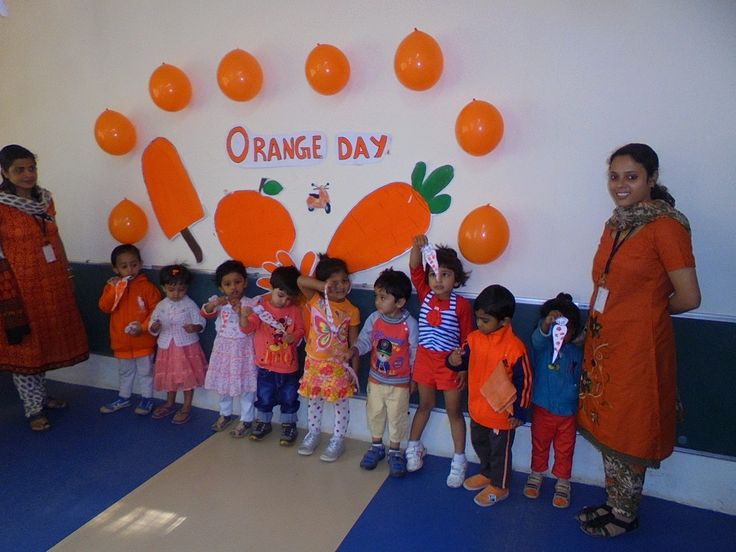 a group of children standing in front of an orange day sign