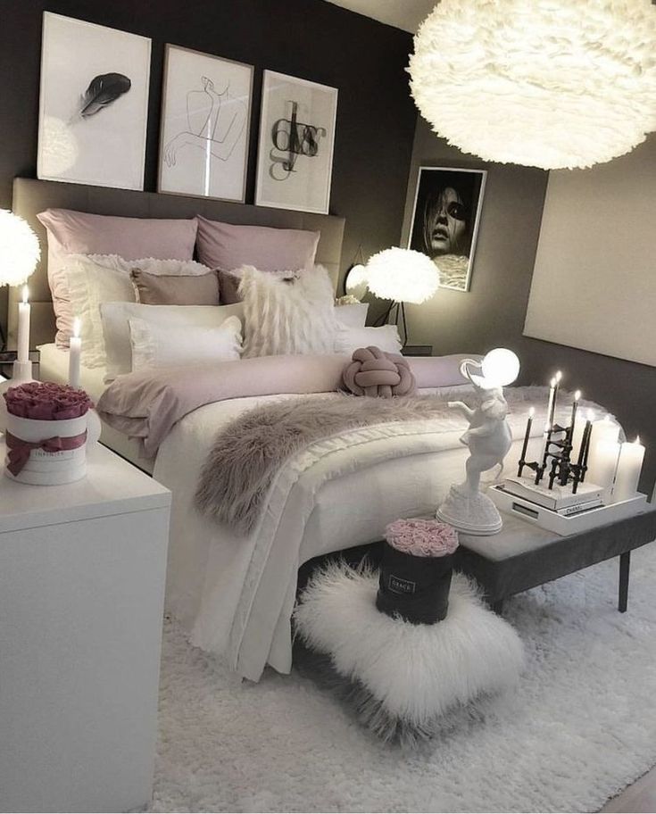 a bedroom decorated in white and grey with candles on the bed, rugs and pictures