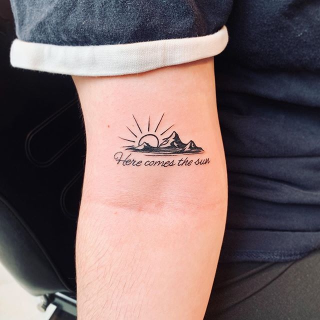 a person with a tattoo on their arm that reads, hope comes the sun and there is a mountain in the background