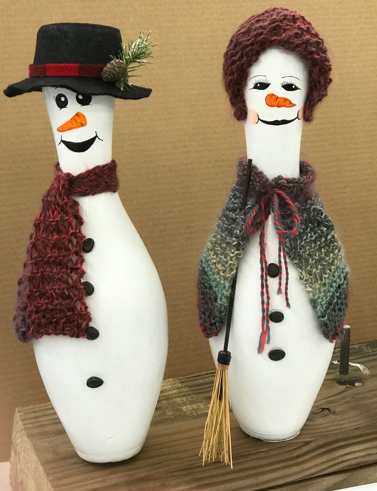 two snowmen wearing hats and scarves are standing next to each other on a table