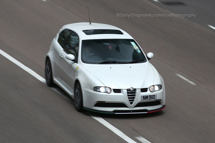 a white car driving down a road next to a forest