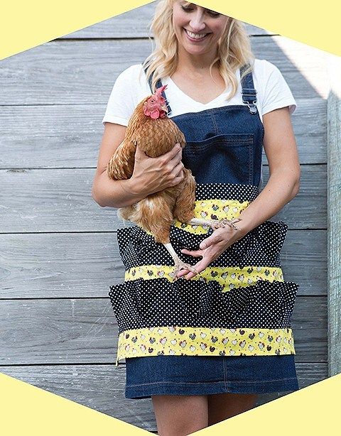 a woman is holding a chicken in her hands while wearing overalls and a white t - shirt