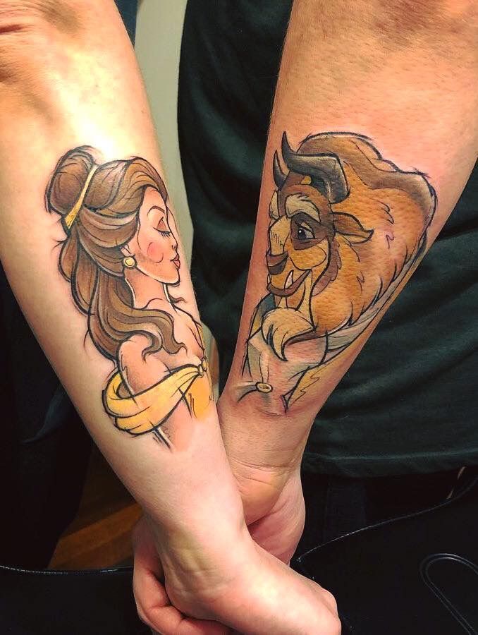 two people are holding hands with tattoos on their arms, one is wearing a yellow ribbon and the other has a brown bear