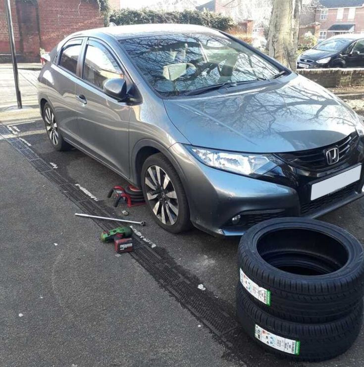 a car is parked on the side of the road with two tires next to it