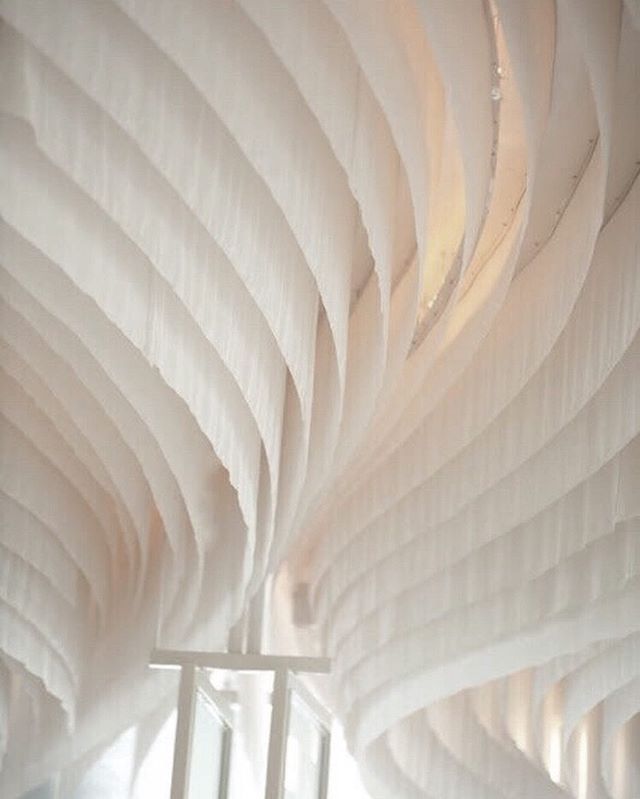 a room filled with lots of white fabric hanging from the ceiling next to a window