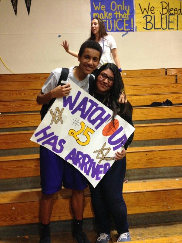 two people holding a sign in front of some bleachers