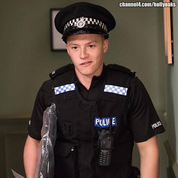 a police officer is standing in the hallway with his knife and helmet on, looking at the camera