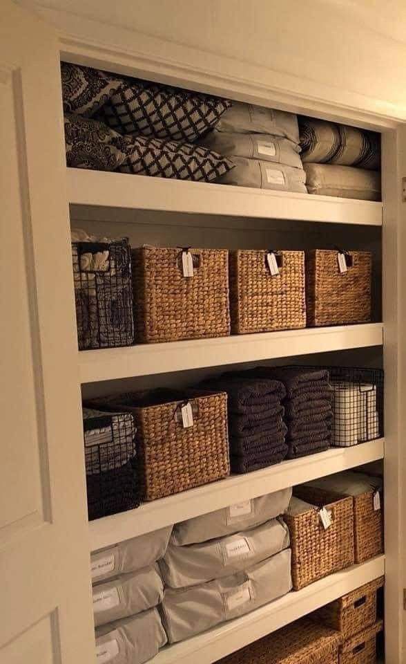 an organized closet with baskets and towels