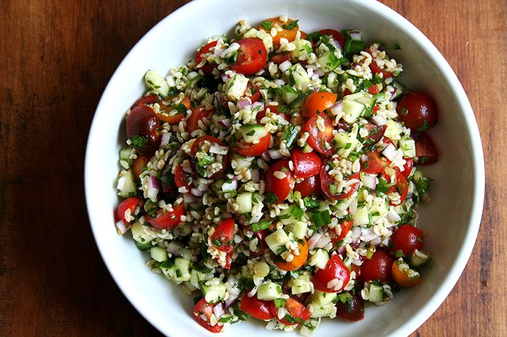 a white bowl filled with salad on top of a wooden table