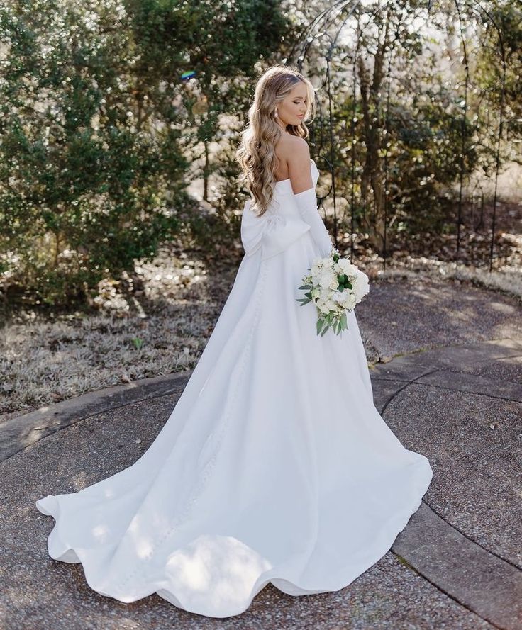 a woman in a white wedding dress is standing on the ground with her back to the camera