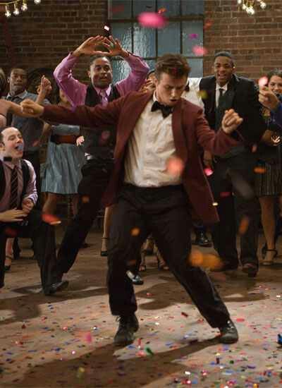 a man in a tuxedo is dancing with confetti all around him