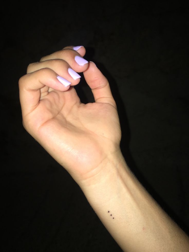 a woman's hand with pink and white nail polish holding her wrist up in the air