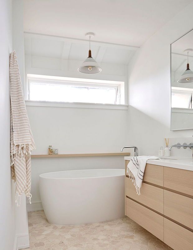 a white bath tub sitting under a bathroom mirror