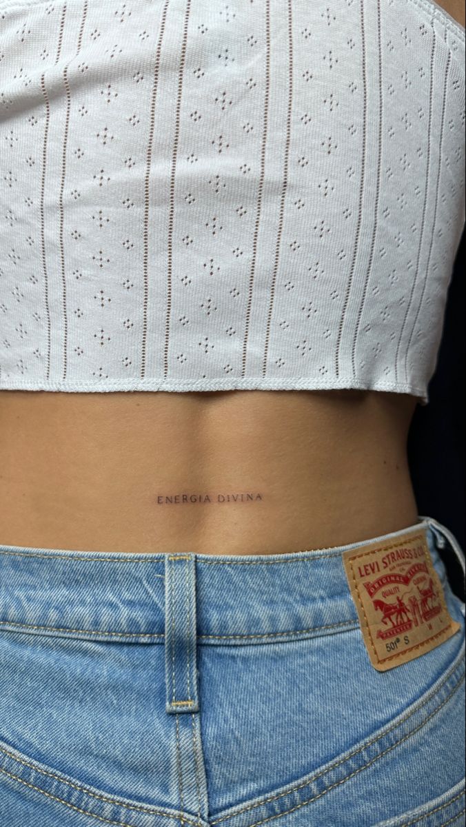 the back of a woman's stomach with a small tattoo on it