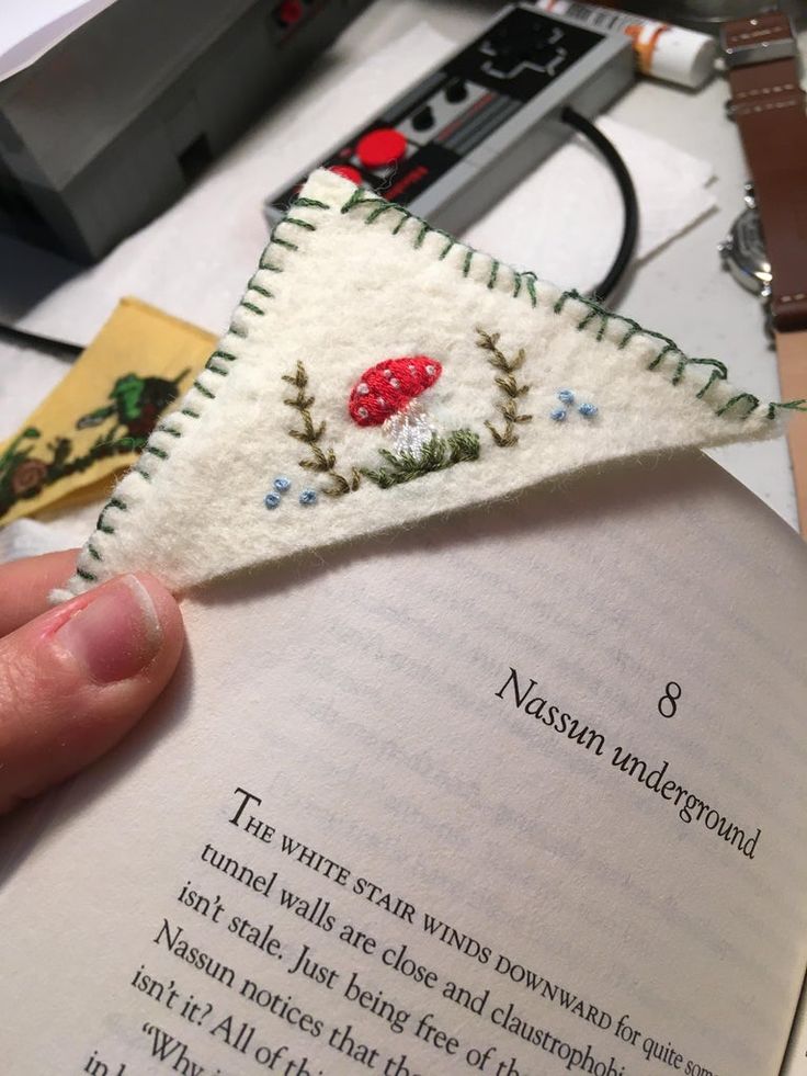 someone is holding an open book with a small piece of fabric on top of it