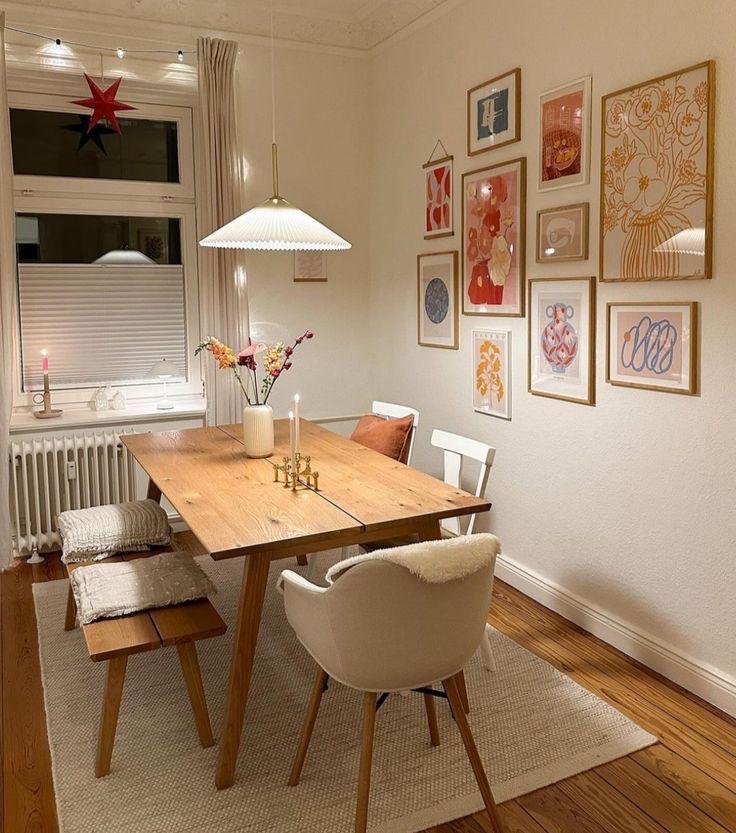 a dining room table with chairs and pictures on the wall above it, along with other furniture