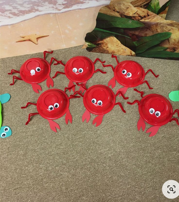 there are many red plastic plates with eyes and arms on the floor next to some plants