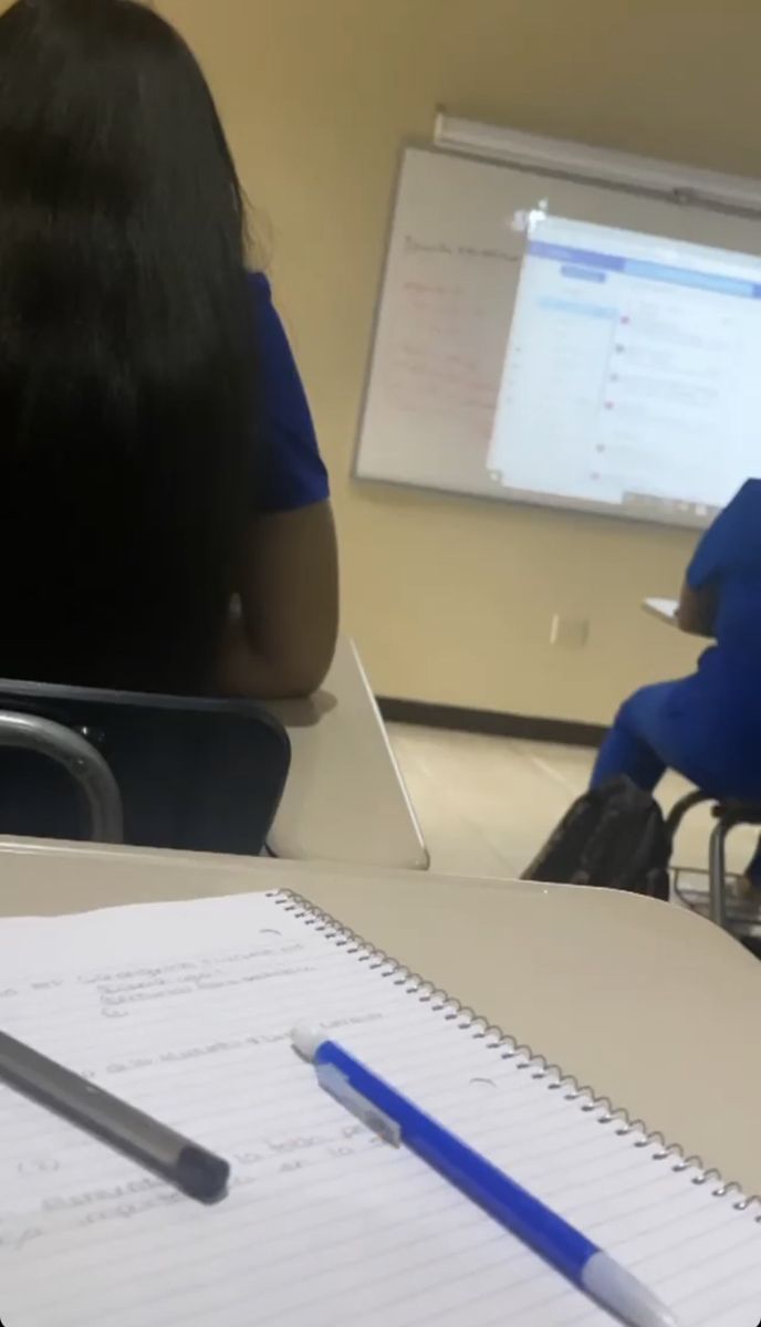 a person sitting at a desk in front of a computer monitor with a pen and paper on it