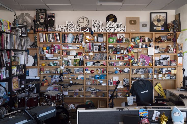 a room filled with musical equipment and lots of clutter on the wall behind it