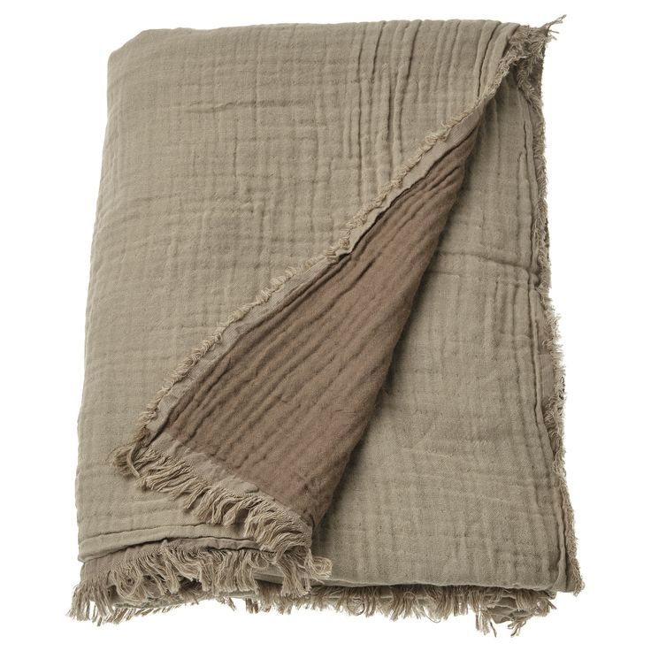 a blanket with fringes is folded on top of a white surface and has a light brown color